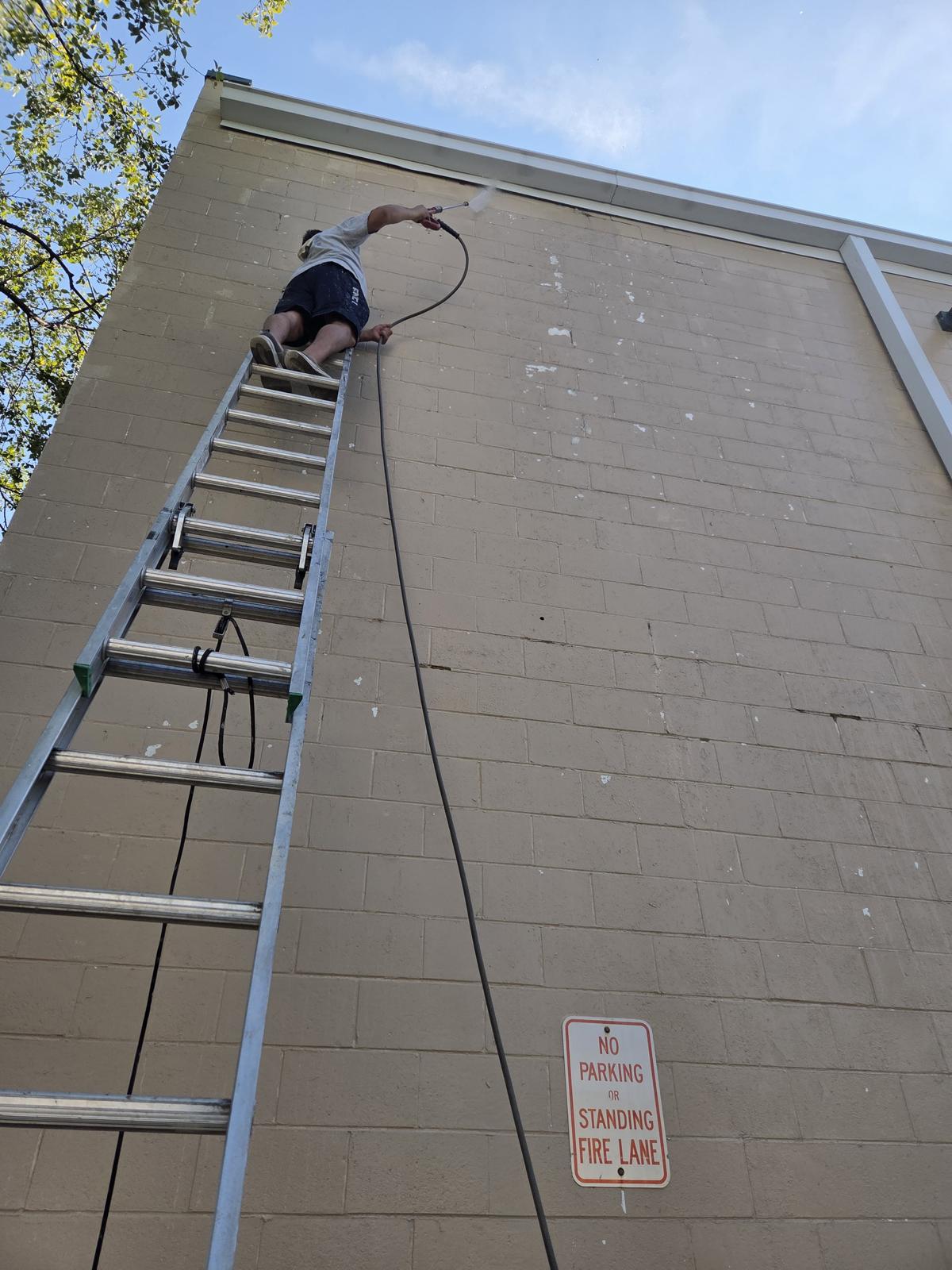 Roy Painting Services crew member painting a commercial building exterior