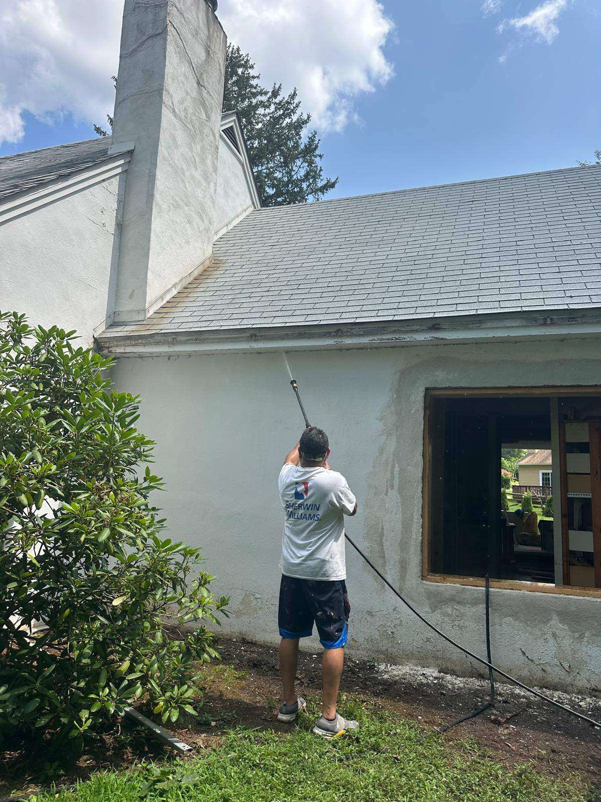 Roy Painting Services crew member pressure washing a home exterior in Coatesville, PA